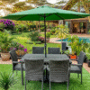 A 6-seater green rattan garden dining set with a central green umbrella on artificial turf, next to a luxury pool and a tropical-themed garden patio.