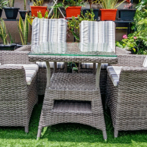 Four high-back wicker chairs with striped cushions arranged around a square glass-top patio table with a built in pocket
