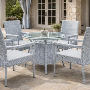 A 4-seater light grey and white rattan dining set with a round glass-top pedestal table on a stone-tiled luxury patio.